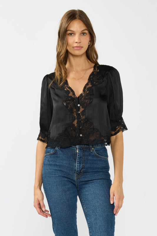Woman wearing a black lace blouse and blue jeans on a white background