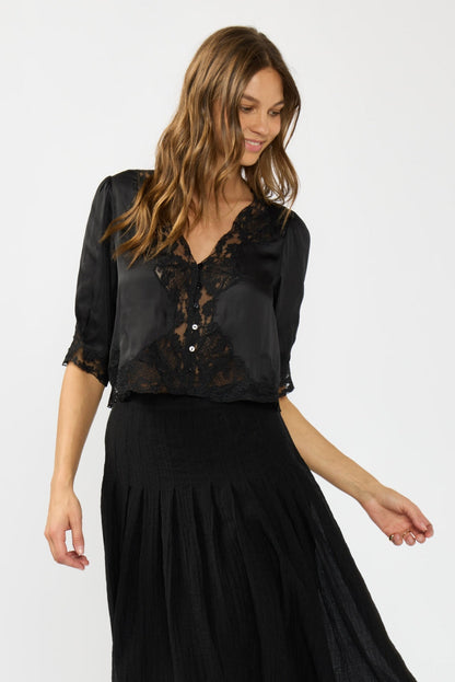 Woman wearing a black lace top and black skirt on a white background