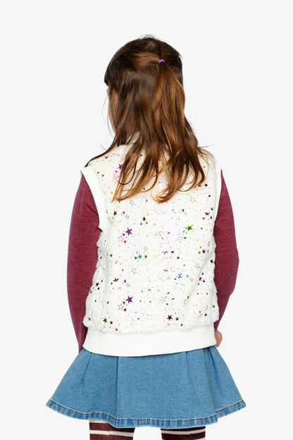 Child wearing a white vest with colorful star patterns, maroon long-sleeve shirt, and blue skirt on a white background.