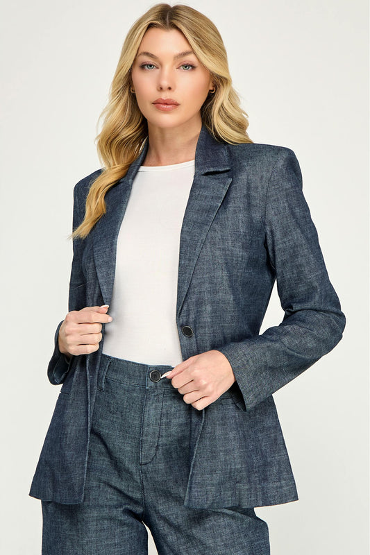 A blonde woman models a matching stargazer colored lennox blazer and trousers set with a white top, photographed against a light gray studio background.