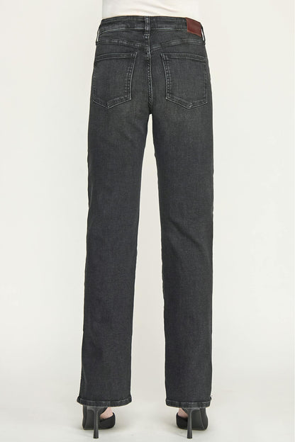 Rear view of a person wearing dark ash straight-leg cigarette jeans with a white top and black high heels, shown against a plain light gray studio background.