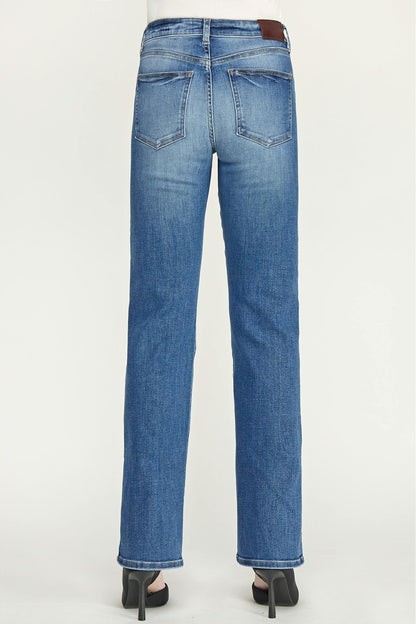 Back view of a person wearing blue straight-leg cigarette jeans in baja color and black high heels against a light gray studio background.