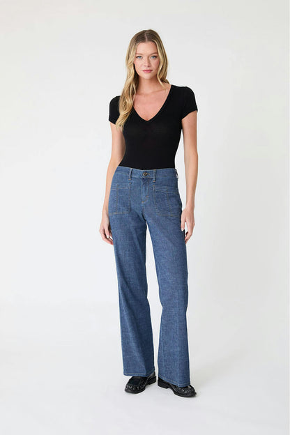 Woman wearing a black top and Sarah pant blue jeans in stargazer color on a white background