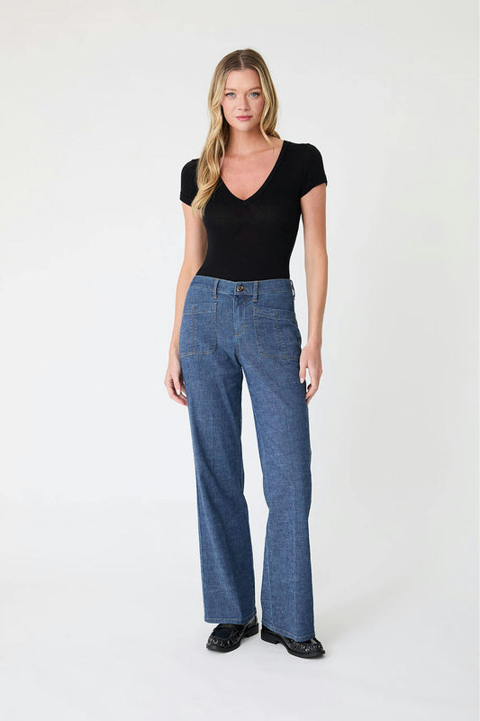 Woman wearing a black top and Sarah pant blue jeans in stargazer color on a white background