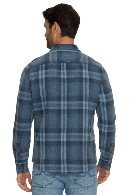 A man viewed from the back wearing a Brundidge blue and gray plaid long-sleeve button-up shirt and light blue jeans against a white background.