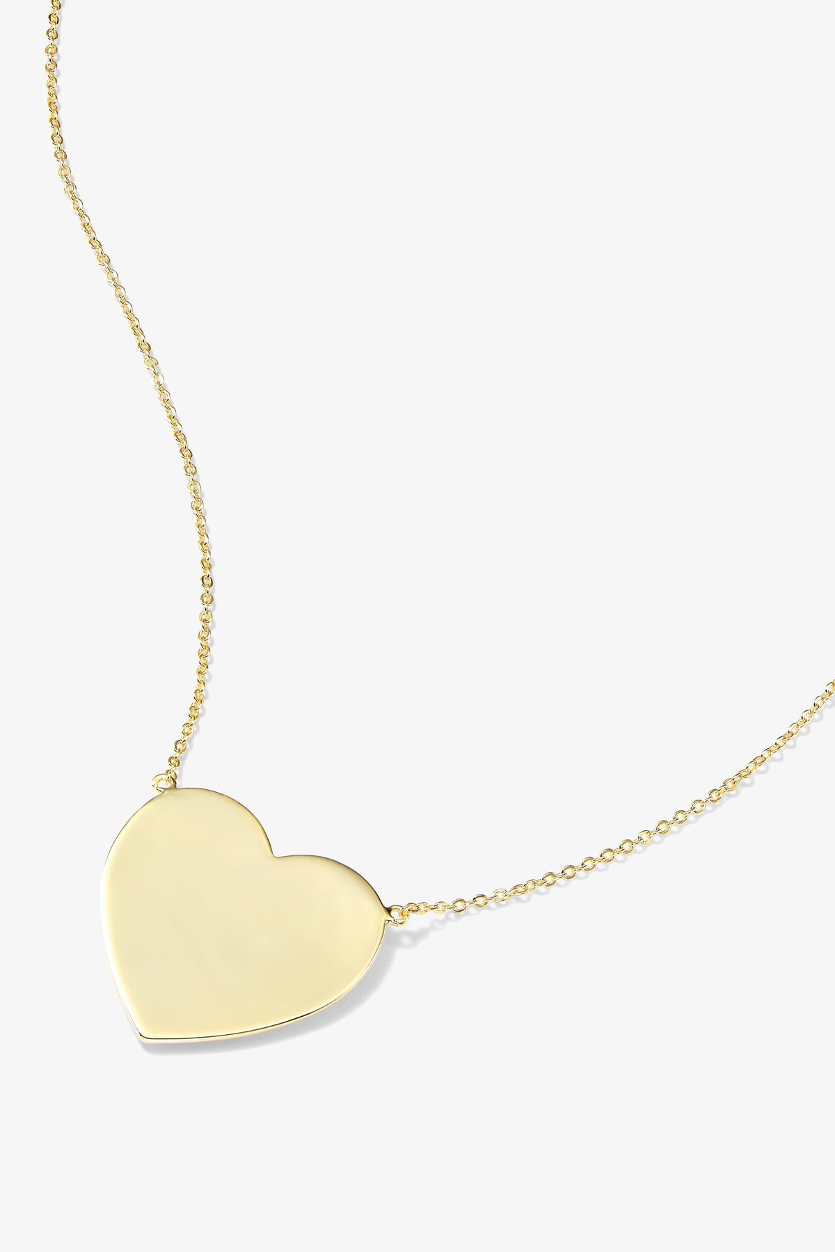 A gold heart-shaped pendant necklace on a delicate gold chain, shown against a light gray background.