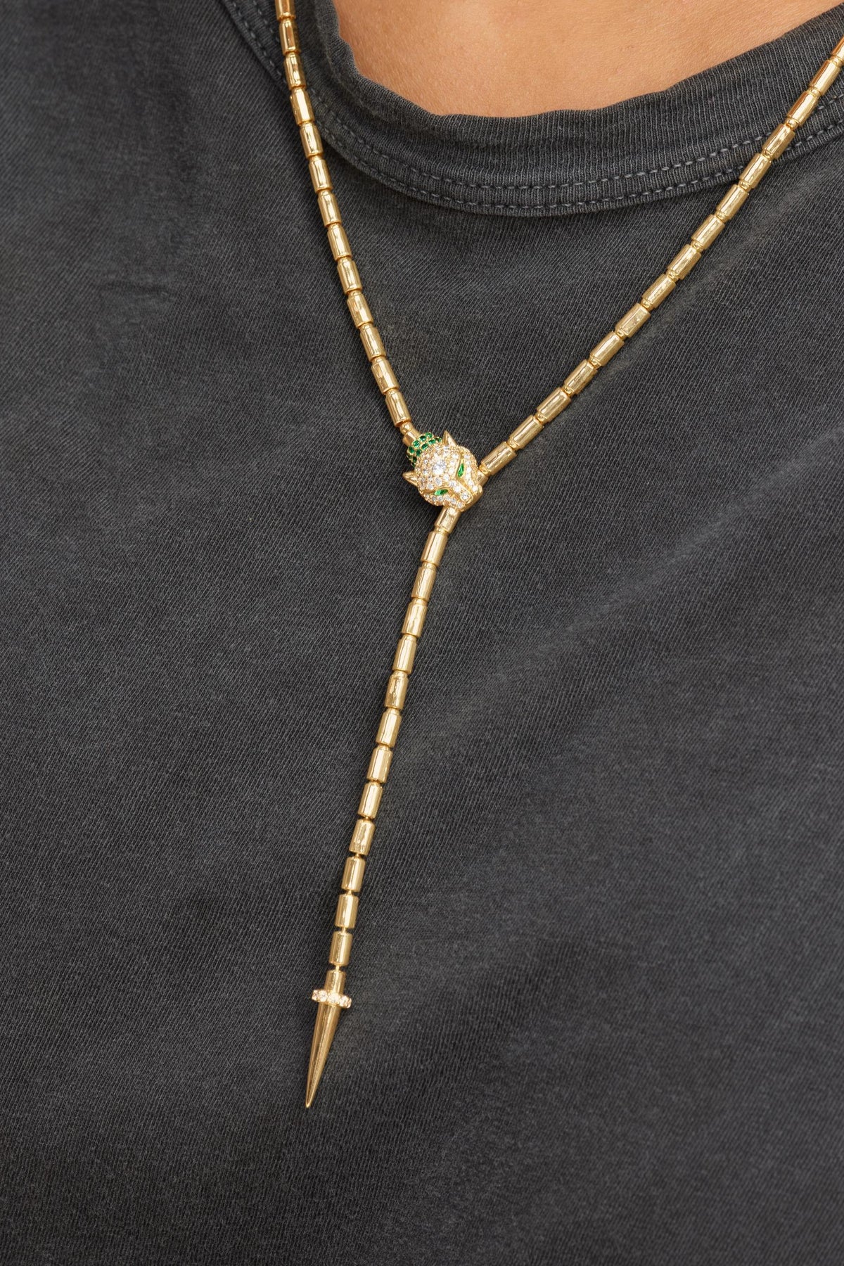 Jaguar Bolo Gold lariat necklace with a green gemstone on a black background