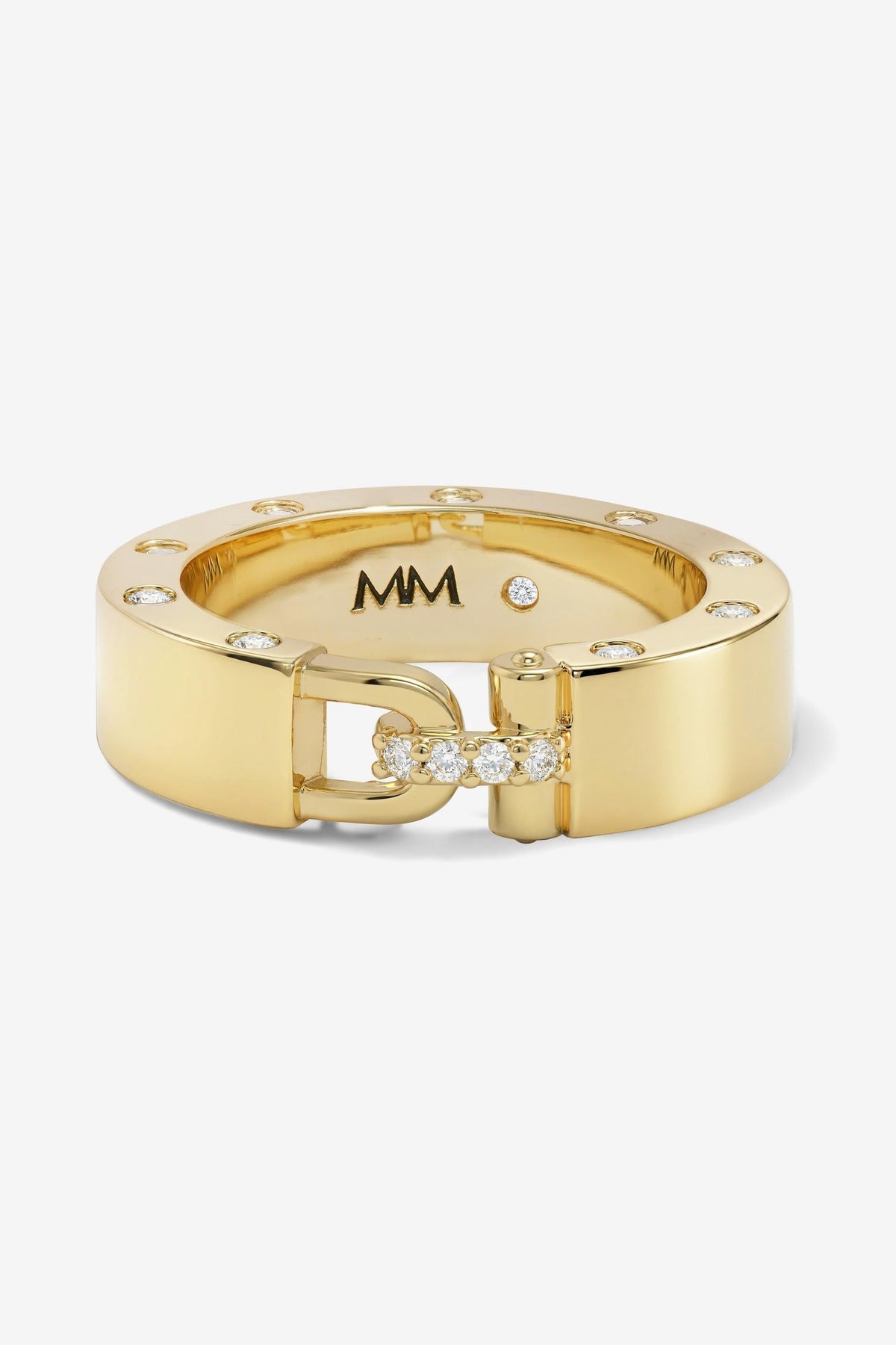 An Ashley Smooth Lock gold-tone ring with a wide band, a D-shaped clasp, and small clear stones, shown on a light gray background. The inside of the ring is marked with 'MM'.