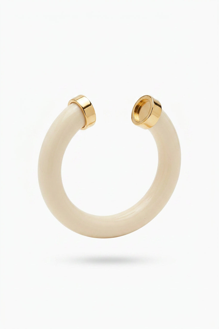 An ivory open cuff bracelet with polished gold metal end caps, shown against a plain white background.