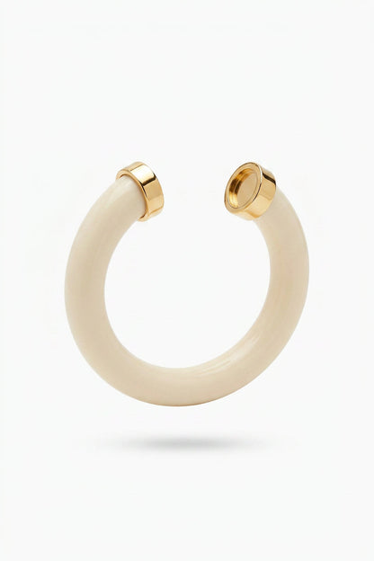 An ivory open cuff bracelet with polished gold metal end caps, shown against a plain white background.