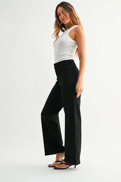 Woman wearing a white tank top with black hidden pocket trouser pants and black heeled sandals shown from the side 