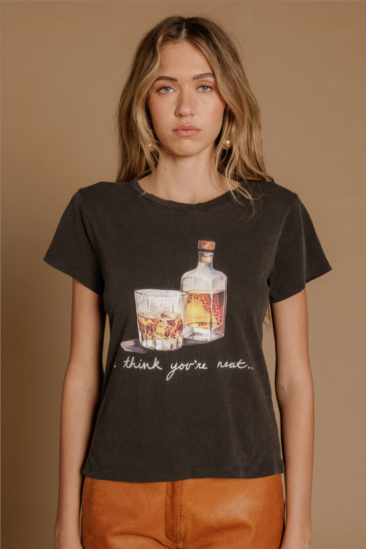 Woman wearing a vintage black "I think you're neat" tshirt featuring an old fashioned drink graphic paired with burnt orange shorts,
