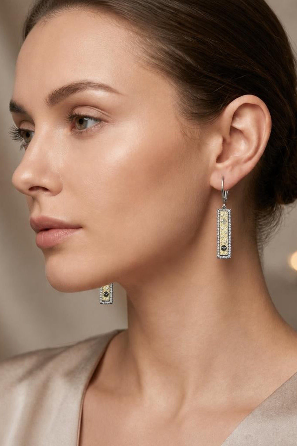 Woman wearing elegant pendant soleil id earrings with a soft focus background