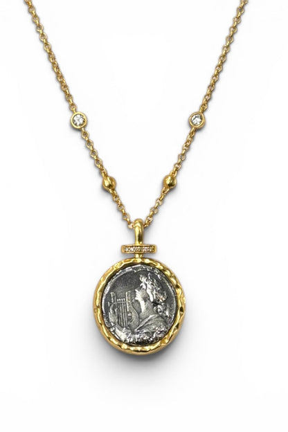 Gold Liora coin necklace with a pendant featuring an engraved design on a white background
