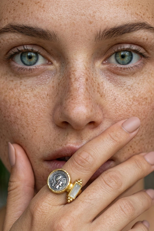 Close-up of a woman's face with freckles wearing a selene rainbow moonstone gold & silver coin ring.