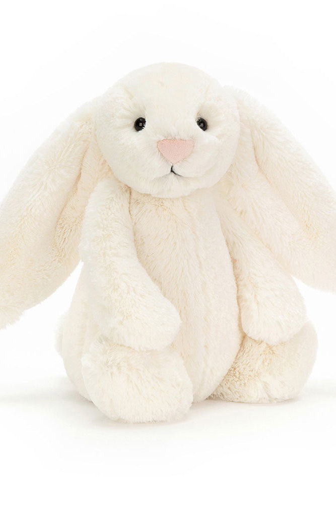 A cream-colored plush bunny stuffed animal with long floppy ears, black embroidered eyes, and a small pink nose, sitting against a clean white background.