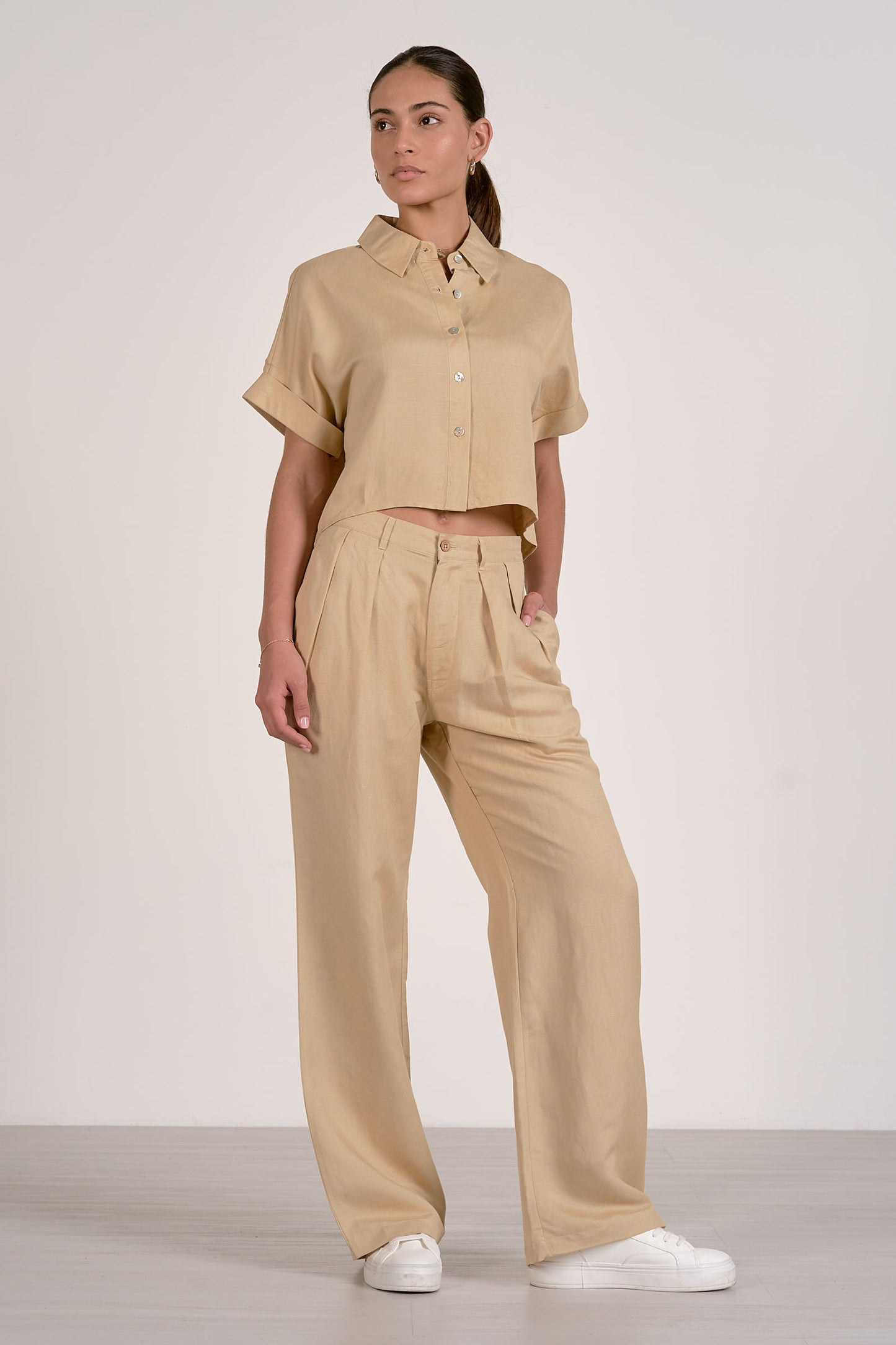Front view of woman wearing an oatmeal button up shirt shirt and pants set on a white background