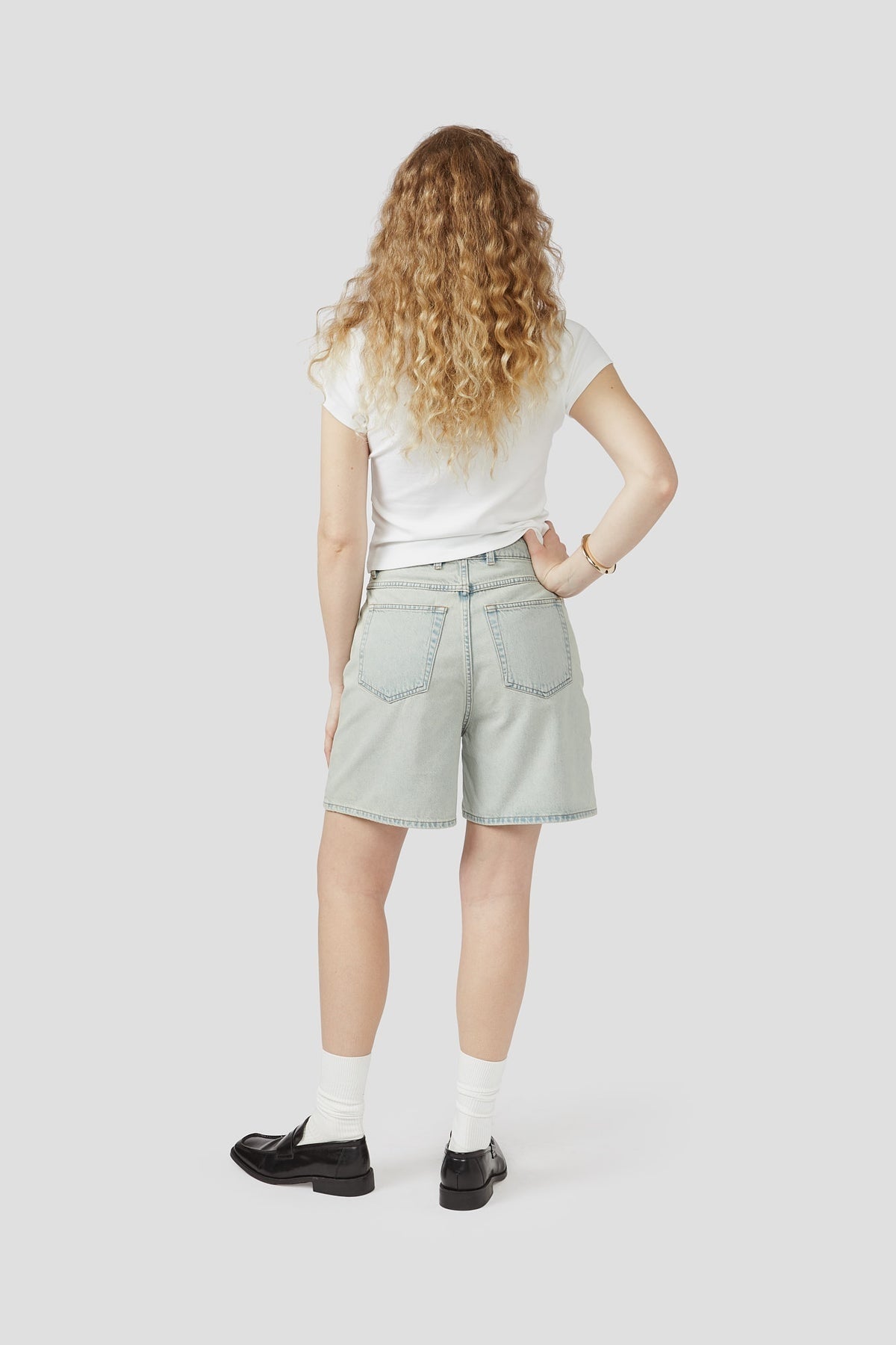 Light-wash denim shorts, back view, with belt loops and patch back pockets
