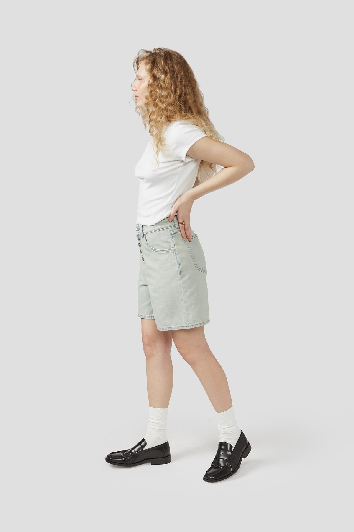 Light-wash denim shorts, side view, with belt loops and button fly