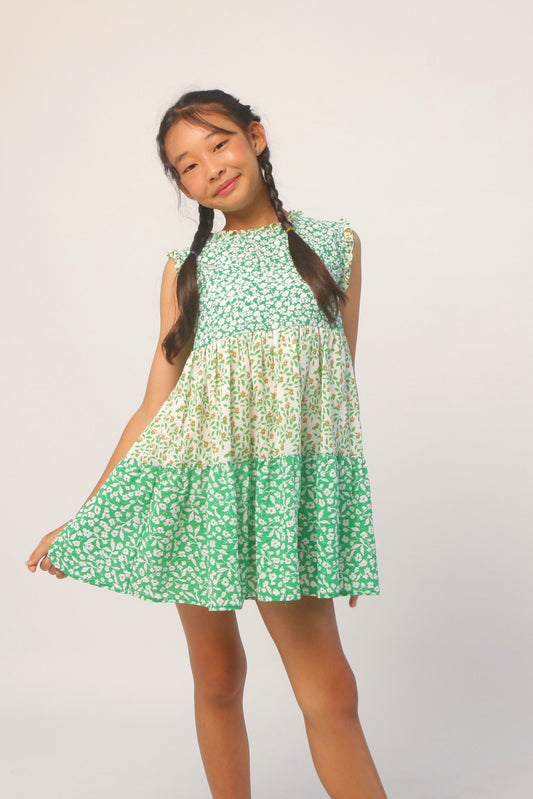 Young girl wearing a green floral dress against a plain background