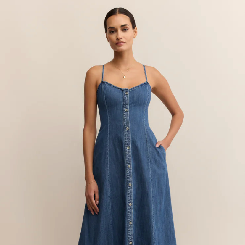 Woman wearing a blue denim dress against a beige background