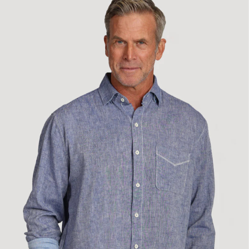 Man wears a blue chambray button down on a white backdrop
