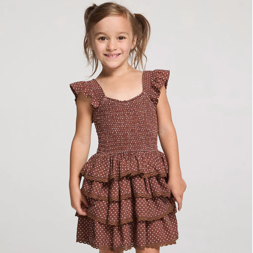 A young girl wears a brown ruffled polka dot dress