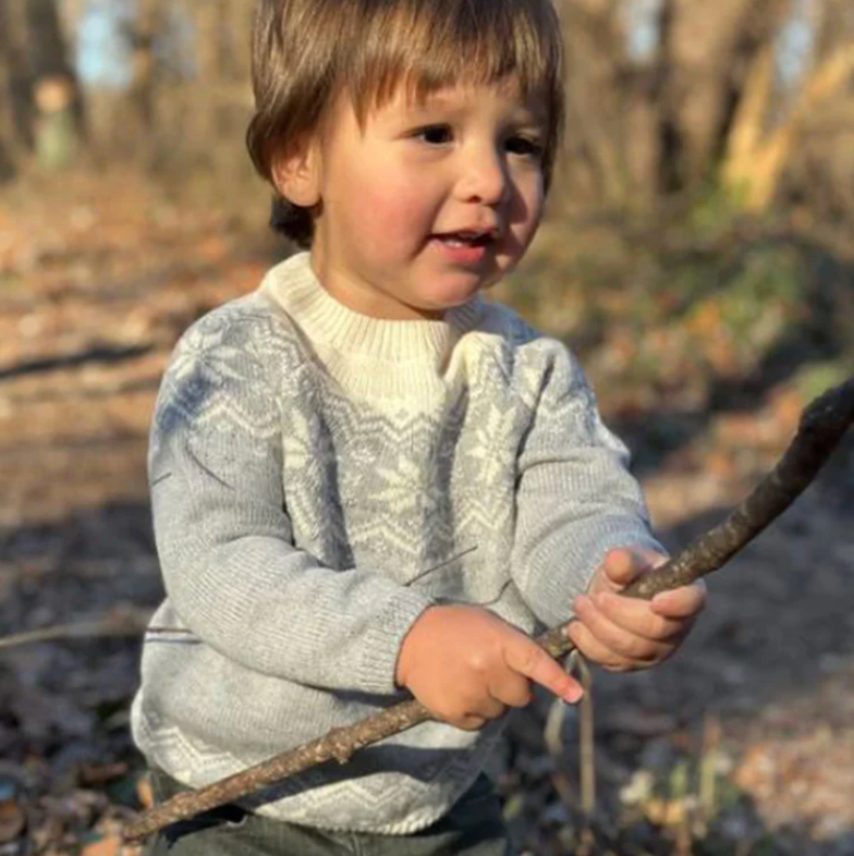 Child holding a stick outdoors with a natural background