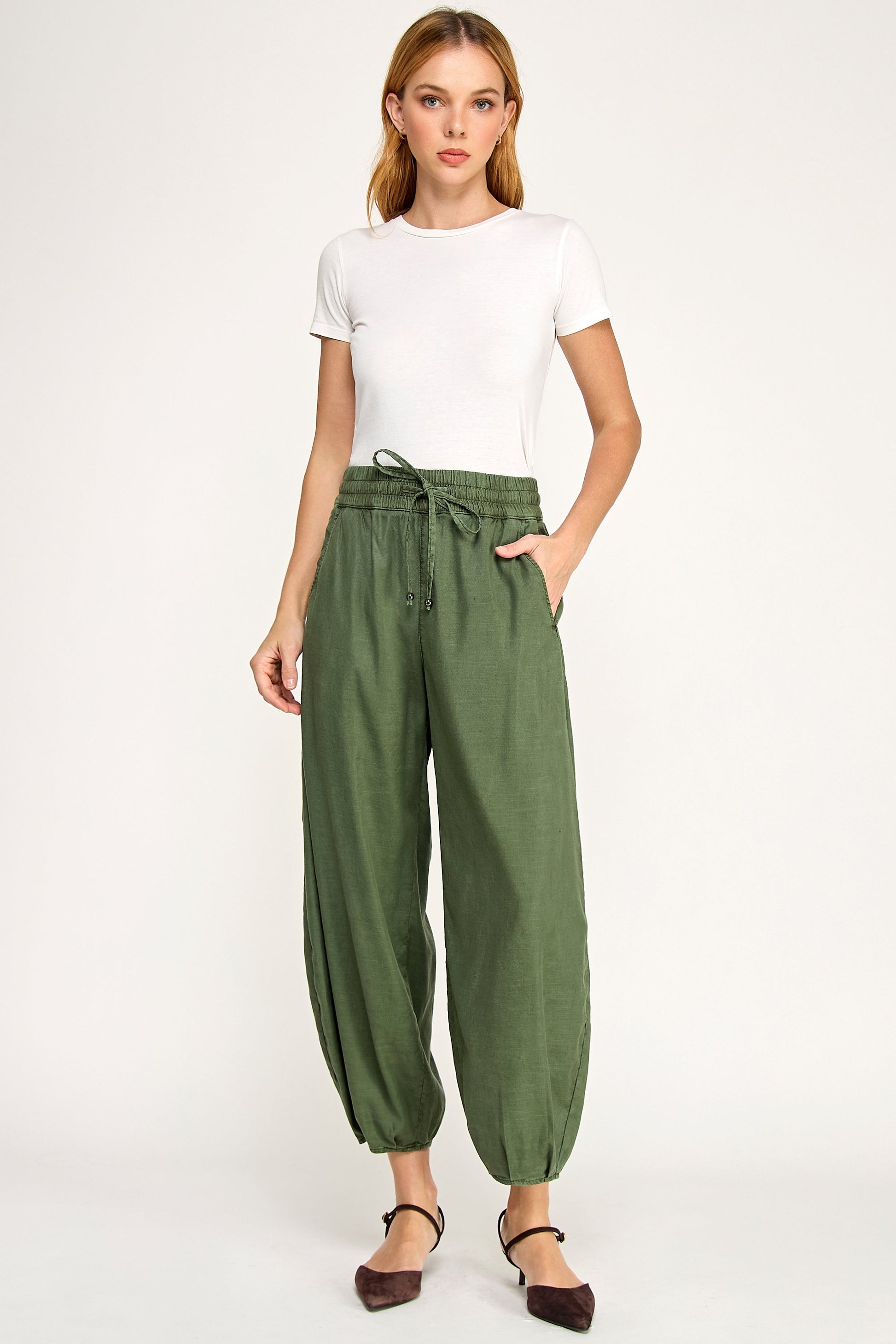 Woman wearing a white t-shirt and avocado green ellie mini balloon pants on a white background