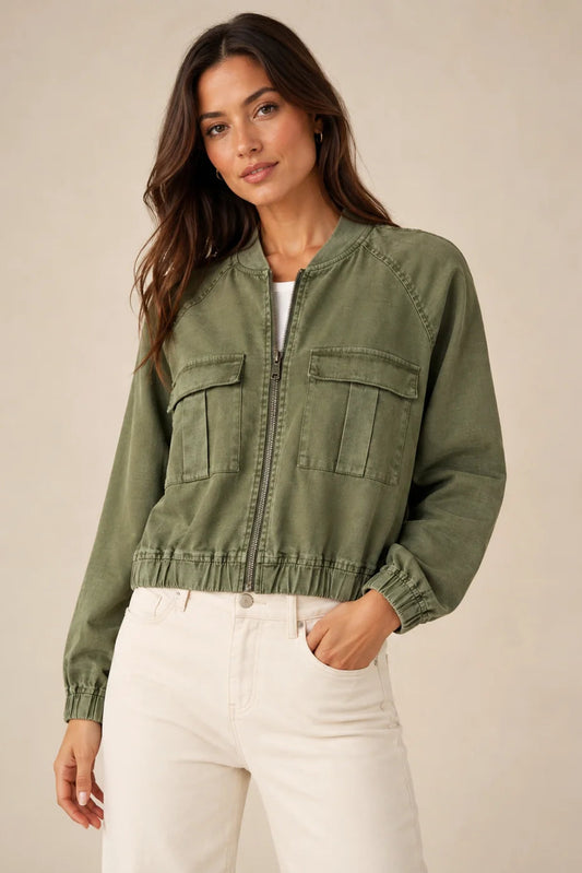 Woman wearing alex bomber jacket with zip front in avocado green color with white pants